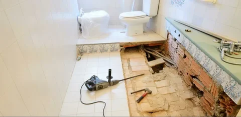 Complete bathroom renovation in progress, showing structural demolition and surface preparation for new custom cabinetry and flooring.
